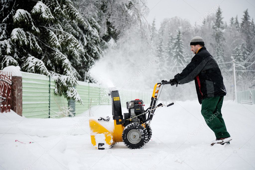 A man operating snow blower in winter