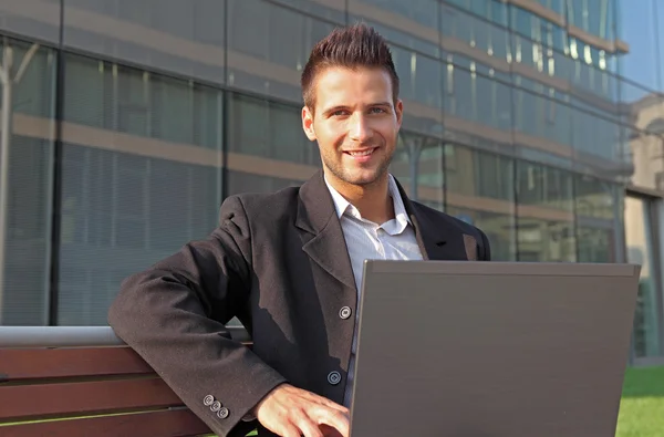 Впевнений бізнесмен посміхається з ноутбуком — стокове фото