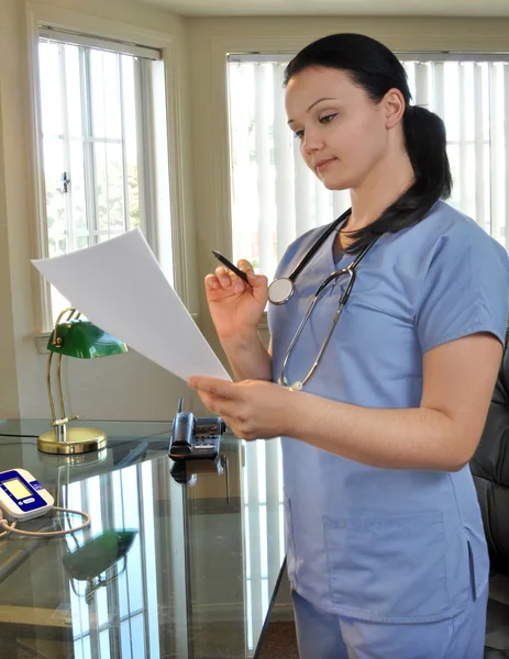 Infirmière regardant un dossier médical — Photo