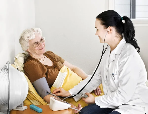 La señora mayor que tiene su presión arterial revisada por un médico — Foto de Stock