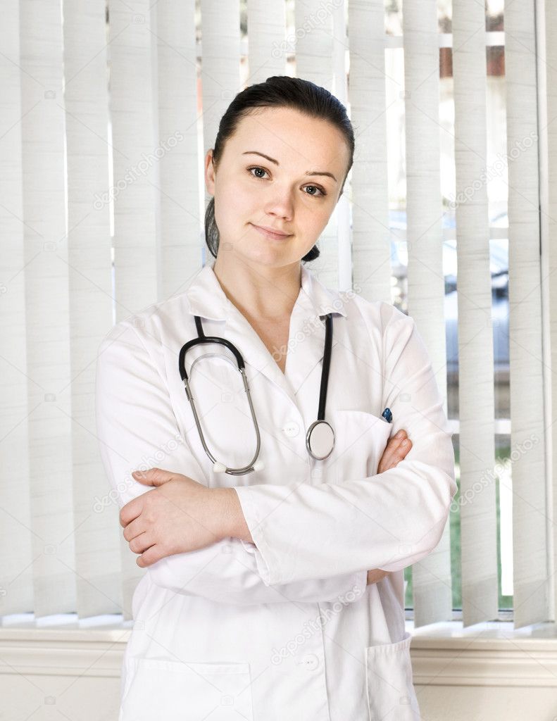 Portrait of female doctor standing in front of office window
