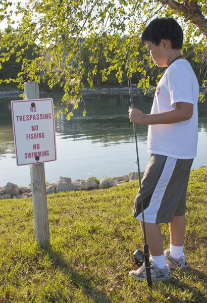 Pojken läsa skylten "inget fiske" — Stockfoto