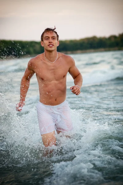 Привлекательный мужчина в нижнем белье на пляже на рассвете . — стоковое фото