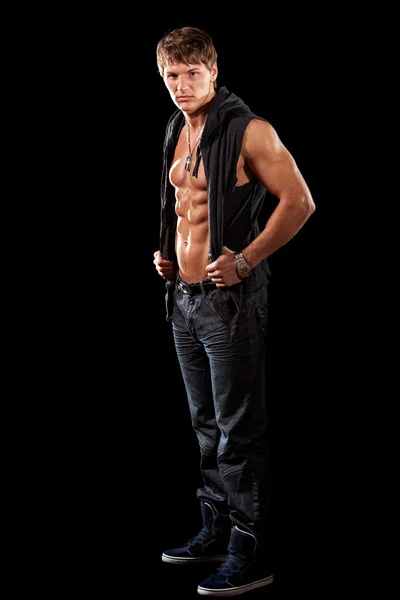 Bodybuilder in jeans with shirt open. Studio shot over black. — Stock Photo, Image