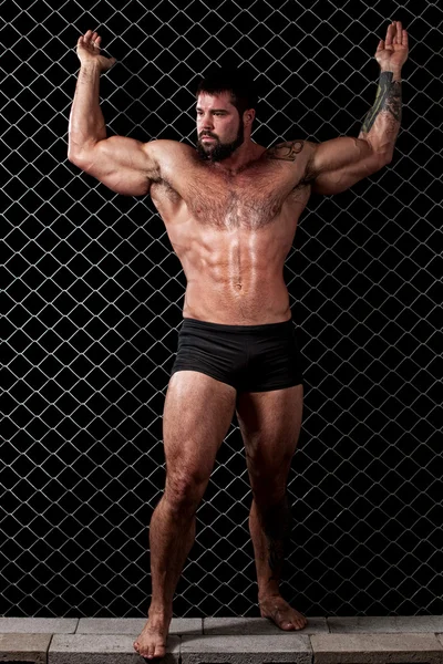 Bodybuilder posiert vor Kettengliedern. — Stockfoto