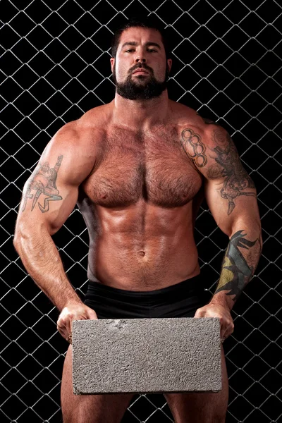 Bodybuilder posing in front of chain link. — Stock Photo, Image