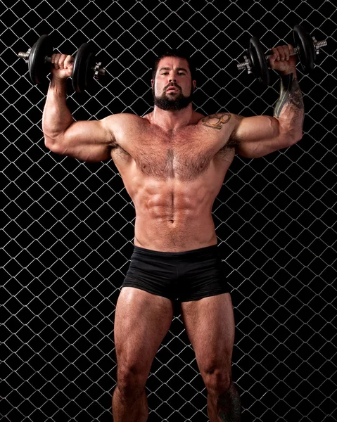 Bodybuilder poseren voor keten link. — Stockfoto