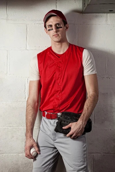 Baseball player in front of concrete block wall. — Stock Photo, Image