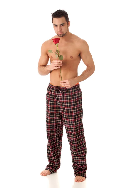 Attraktiver Mann im Schlafanzug mit einer einzigen roten Rose. — Stockfoto
