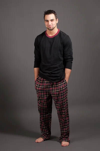 Aantrekkelijke man in pyjama. studio opname over grijs. — Stockfoto