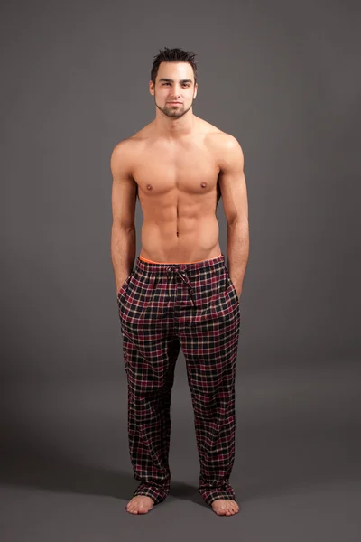 Um homem atraente de pijama. Estúdio filmado sobre cinza . — Fotografia de Stock