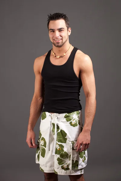 Attraktiver junger Mann in kurzen Hosen. Studioaufnahme über Grau. — Stockfoto