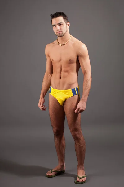 Attractive young man in swimsuit. Studio shot over grey. — Stock Photo, Image