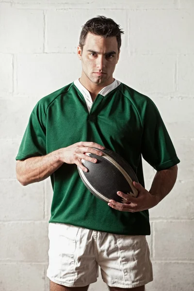 Male rugby player in front of concrete block wall. — Stock Photo, Image