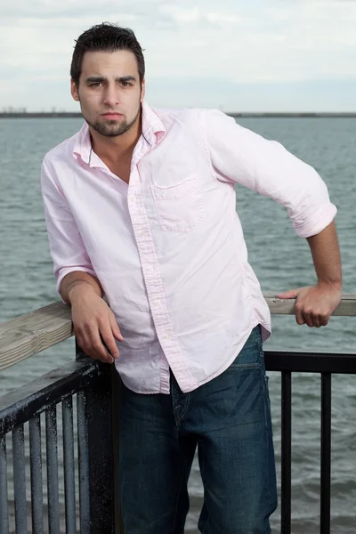 Man in jeans and pink shirt near water. — Stock Photo, Image