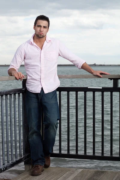 Homem de jeans e camisa rosa perto da água . — Fotografia de Stock