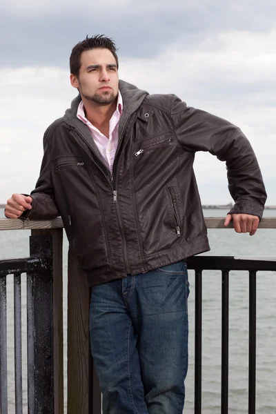 Homem de jeans e jaqueta de couro perto da água . — Fotografia de Stock