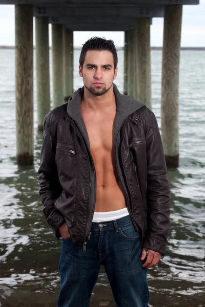 Homme en jean et veste en cuir sous une jetée . — Photo