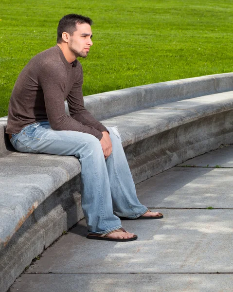 Jonge man zit outsitde op concrete Bank. — Stockfoto