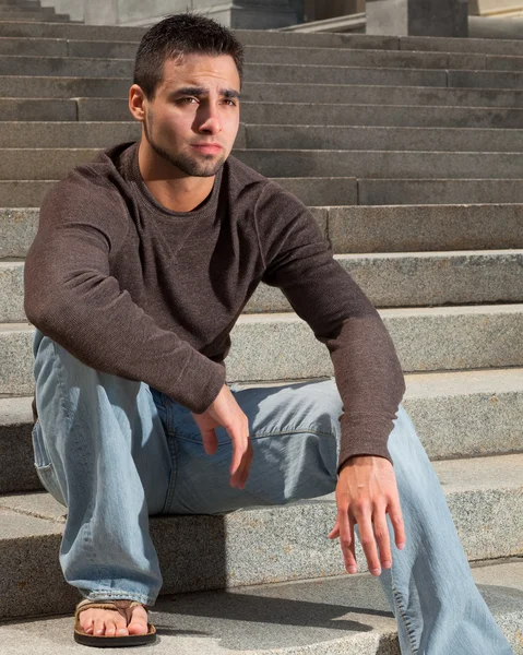 Молодой человек сидит снаружи на большой лестнице . — стоковое фото