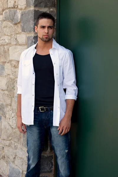 Νεαρός άνδρας outsitde στέκεται μπροστά από το πέτρινο τοίχο. — Φωτογραφία Αρχείου