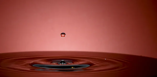 Gota de água no fundo vermelho — Fotografia de Stock