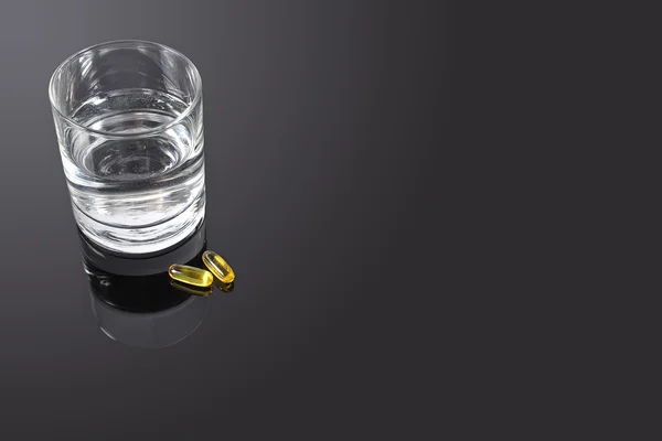Píldoras y vaso de agua — Foto de Stock