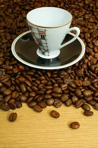 Taza con platito sobre fondo de granos de café —  Fotos de Stock