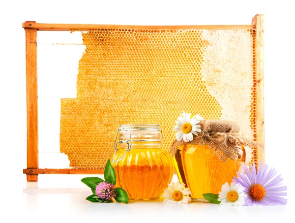 Sweet honey in glass jars and honeycomb with flowers — Stock Photo, Image