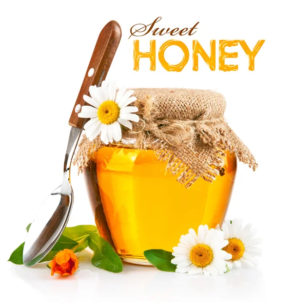 Сладкий мед в стеклянной фляге с ложкой и цветами — стоковое фото