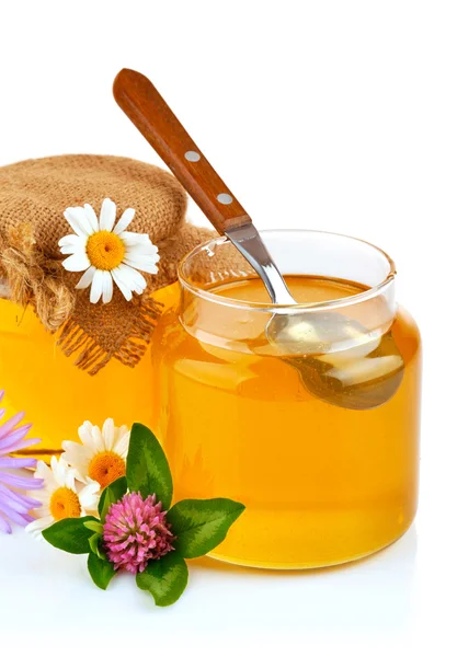 Sweet honey in glass jars with spoon and flowers — Stock Photo, Image