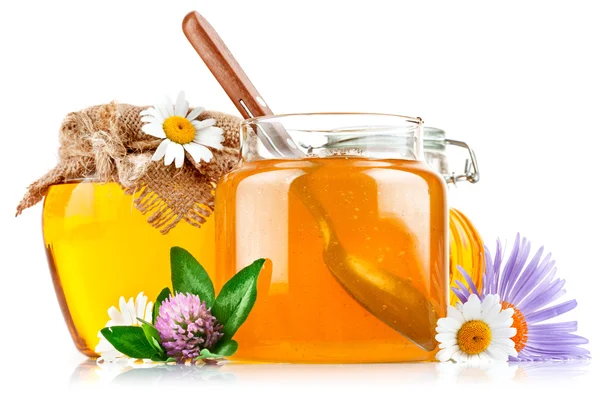 Dulce miel en frascos de vidrio con cuchara y flores —  Fotos de Stock