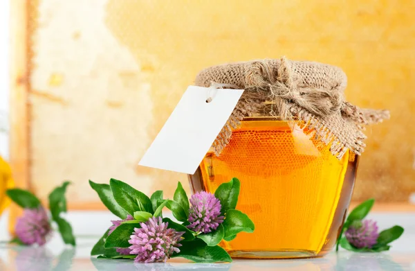 Zoete honing in glazen potten met bloemen — Stockfoto