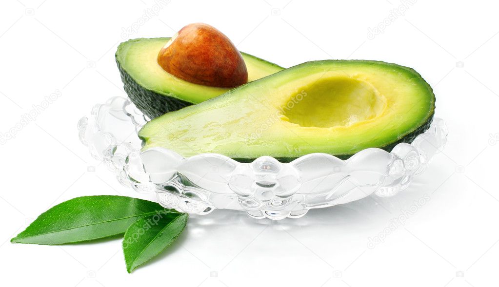 Fresh avocado fruit with green leaves in glass dish