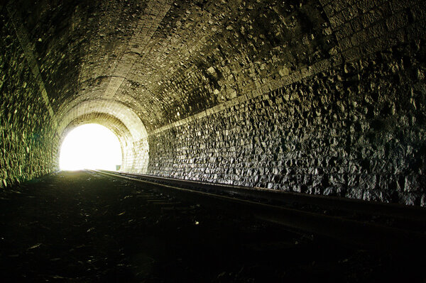 Light at the end of railroad tunnel. Natural lighting.
