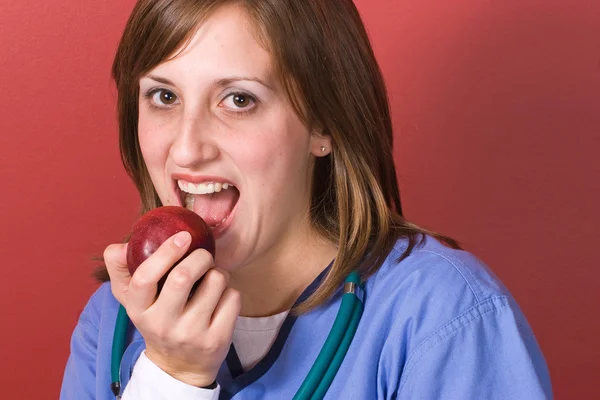 看護師はりんごをかじって — ストック写真