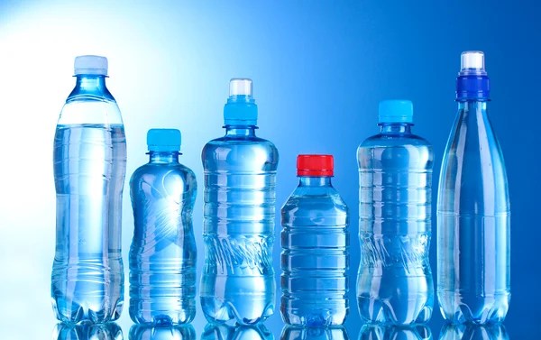 Gruppo bottiglie di plastica di acqua su sfondo blu — Foto Stock