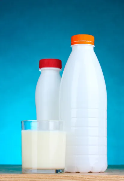 Bardak ve şişe mavi zemin üzerine lezzetli süt — Stok fotoğraf