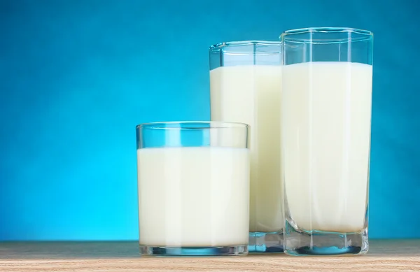 Sabrosa leche en vasos sobre fondo azul — Foto de Stock