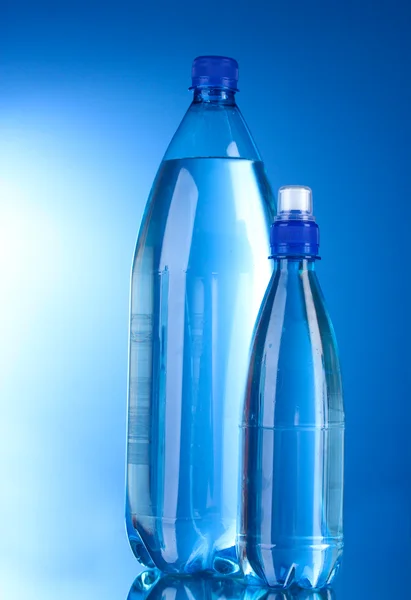 Duas garrafas de plástico de água no fundo azul — Fotografia de Stock