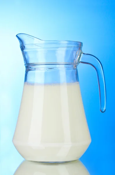 Tasty milk in jug on blue background — Stock Photo, Image