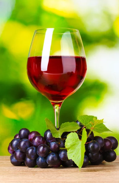 成熟的葡萄和葡萄酒在绿色背景上的玻璃 — 图库照片