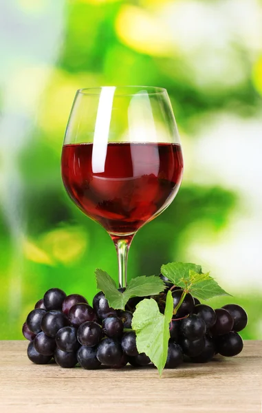 Ripe grapes and glass of wine on green background — Stock Photo, Image