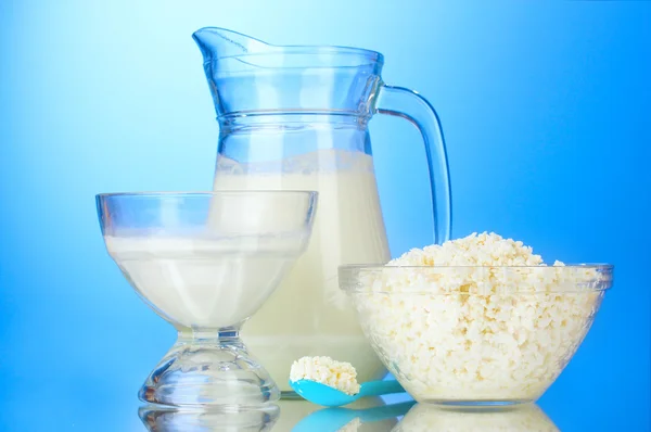 Latte, panna acida e fiocchi di latte su sfondo blu — Foto Stock