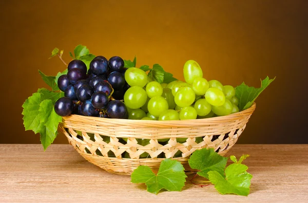 Ripe grapes in a basket on yellow background — Stock Photo, Image