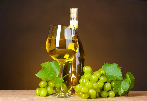 Ποτήρι κρασί, μπουκάλι και σταφύλια σε κίτρινο φόντο — Φωτογραφία Αρχείου
