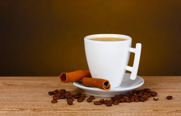 Kopp kaffe, kaffebönor och kanel på träbord — Stockfoto