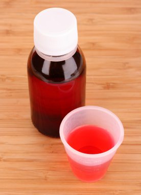 Cough medicine bottle with poured dose clipart