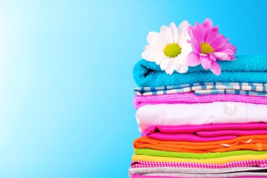 Pile of colorful clothes and flowers on blue background