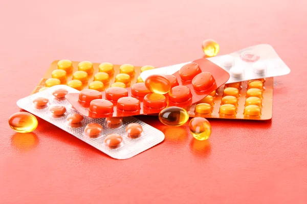 Pílulas medicamento pack pilha closeup no fundo vermelho — Fotografia de Stock